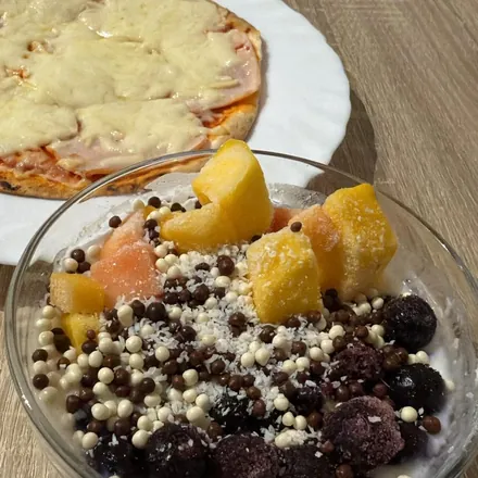 Pizza pequeña con un bol de fruta y yogur