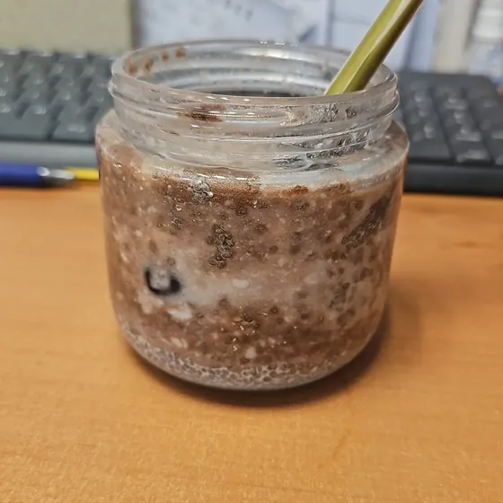 Un bote de chía con cacao y arándanos sobre la mesa del trabajo, junto al teclado
