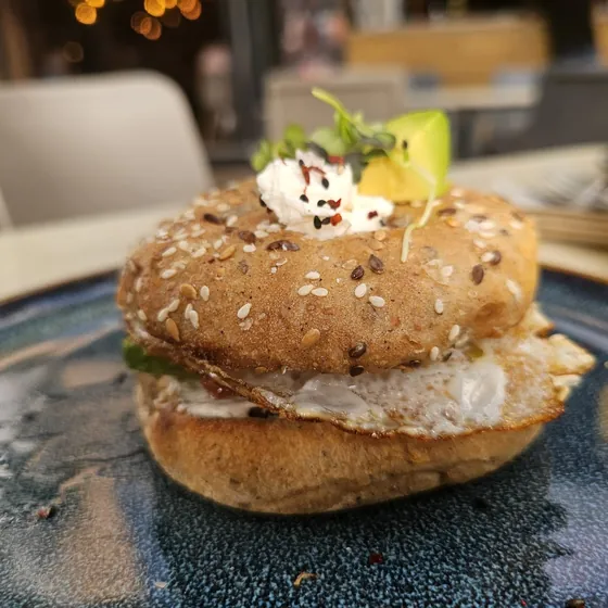 Bocadillo de pan de semillas con huevo y aguacate en la mesa de una cafetería