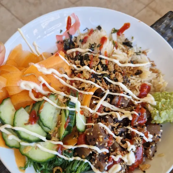Poke de arroz con pescado, pepino, zanahoria y wasabi, en una mesa de terraza