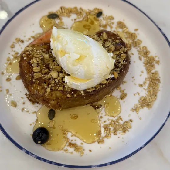 Torrija con miel, crema y granola en un plato de cafetería