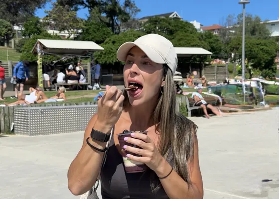Cristina comiendo un helado por la calle, con la playa detrás